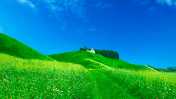 красивый пейзаж - голубое небо и яркая зеленая трава с белым домом на холме