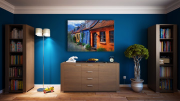 интерьер комнаты, синяя стена, книжные полки, картина, комод, дерево в горшке